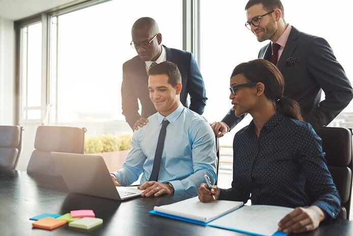 Some happy business people around a computer